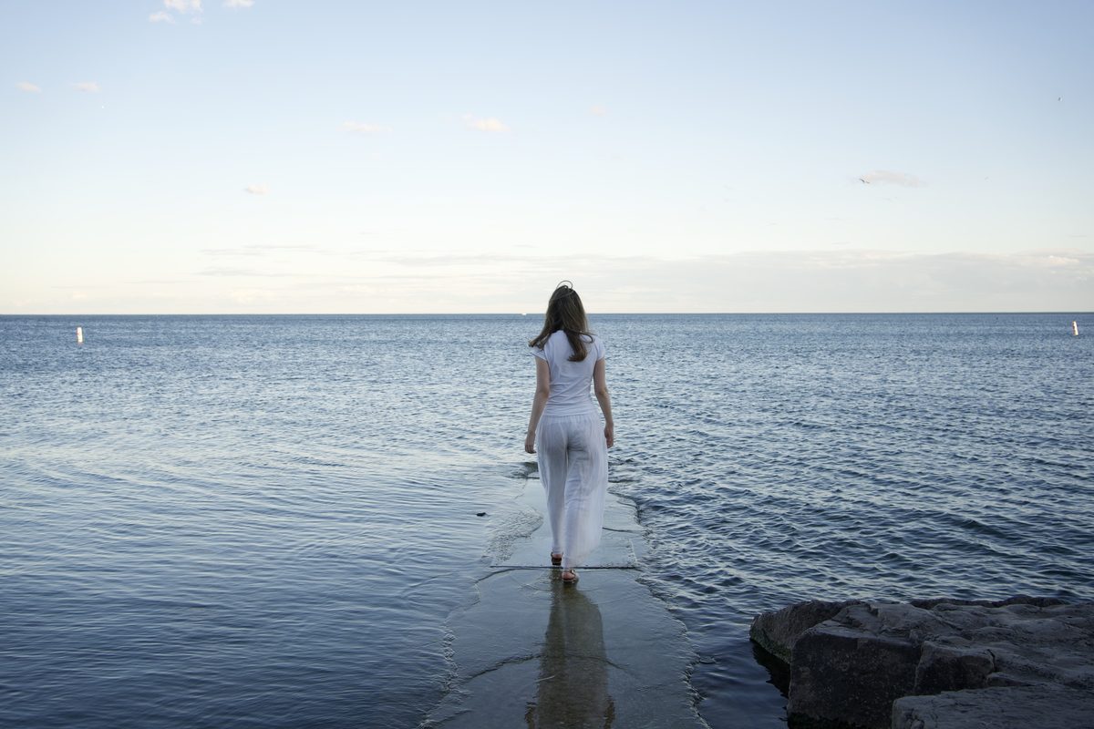 Julia Arbuckle walking barefoot along the water's edge.